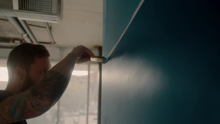 A man using a paintbrush to paint a wall blue