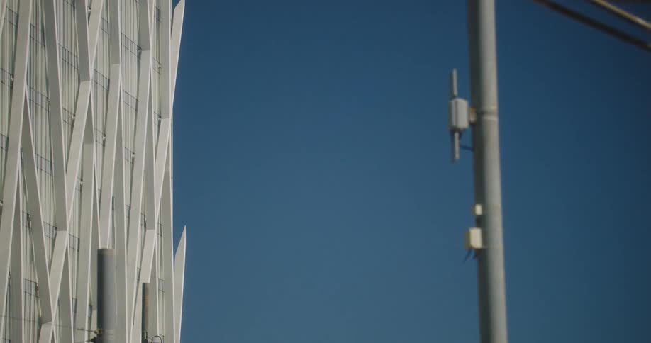 Poles with wires and a sign sit near a large city building