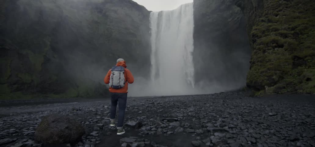 A man walks towards a waterfall