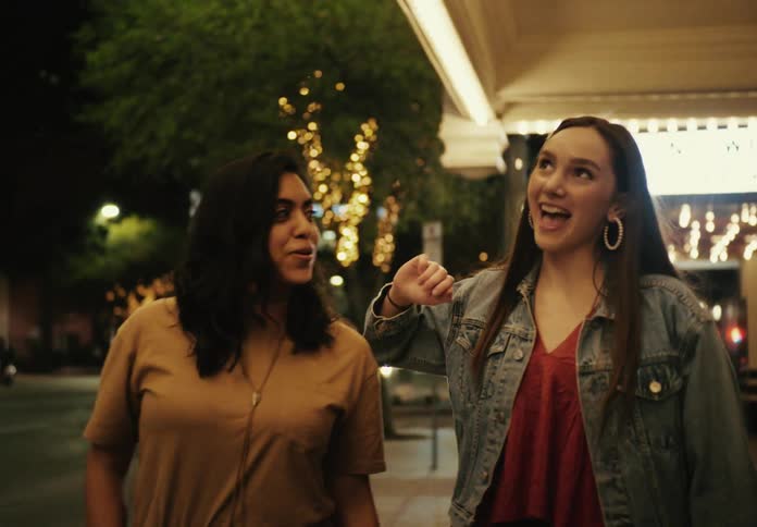 A group of 5 women walking down a city street at night laughing and smiling