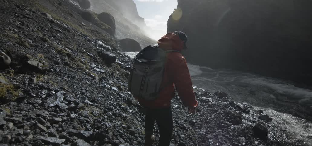 A man is walking down rocky terrain towards a river