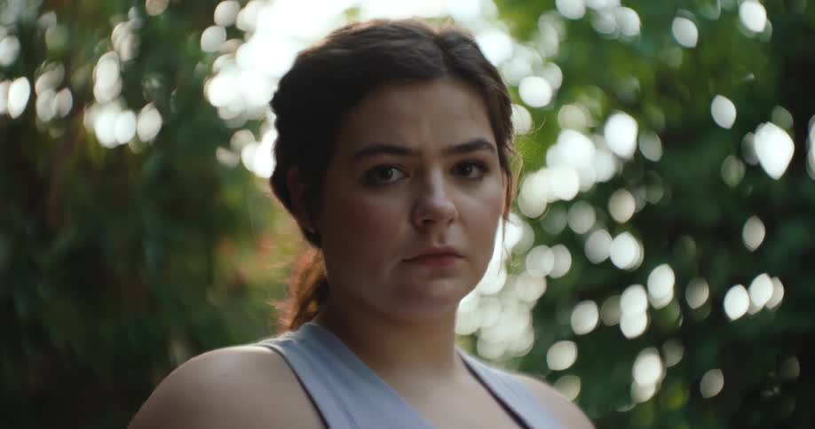 A teenage girl stares and blinks while outdoors by trees