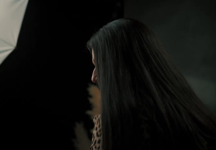 A woman with long hair covering half of her face and then she looks down
