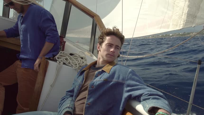 Two young handsome men on a sailboat sailing on the open sea