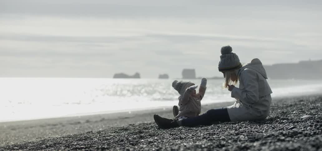 Woman sitting on the beach with her baby