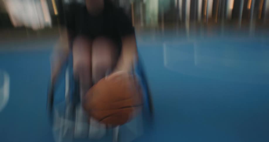 Woman in wheelchair bounces a basketball as the camera follows