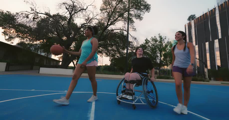 Three friends laugh and smile while going across a basketball court