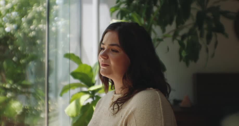 The face of a young woman standing looking at a glass window
