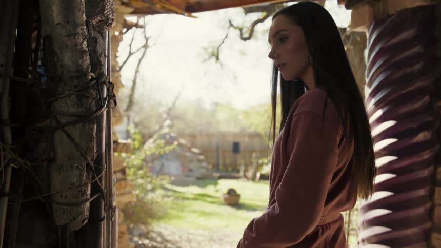 A young woman is inside an enclosure made of junk and she is coming out of it