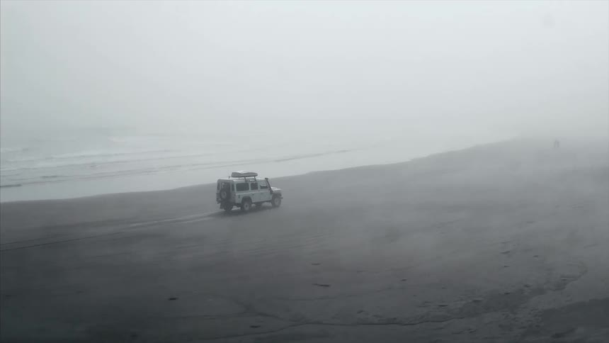 Jeep driving along a beach on a sunny day