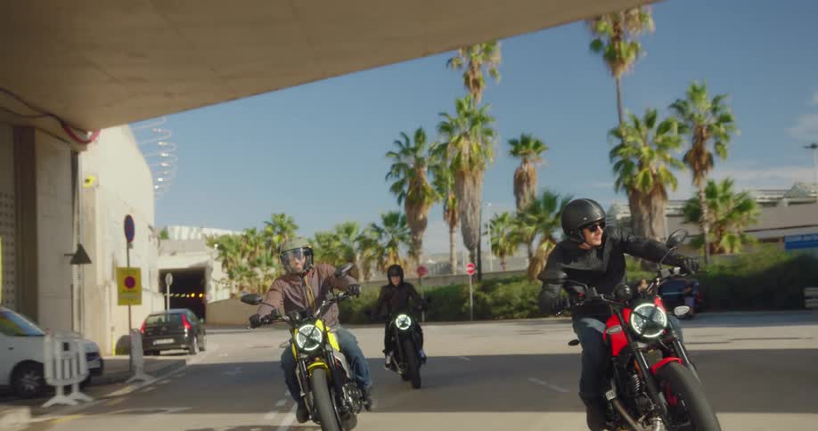 Three bikers on a city freeway coming out of an underpass