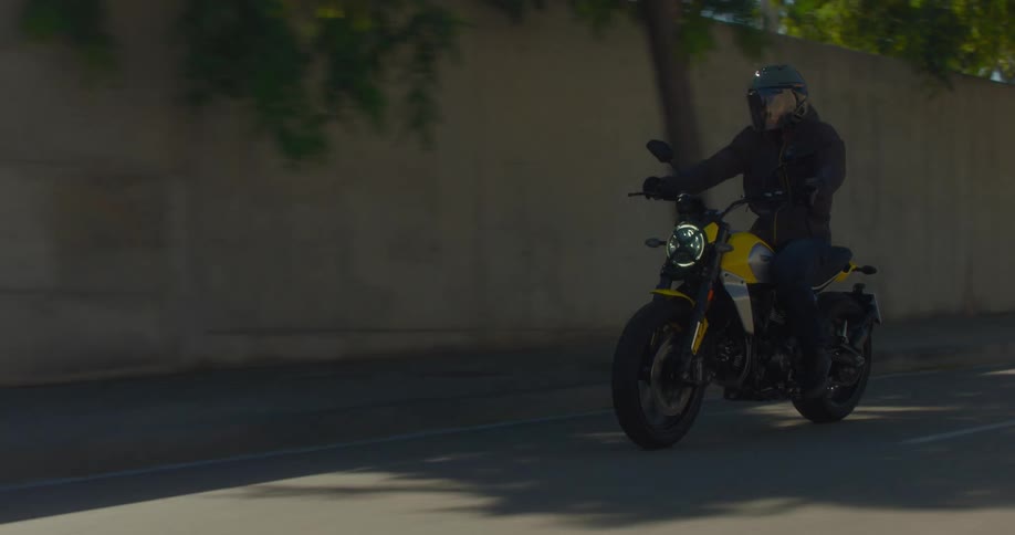 A man rides a motorcycle down the city street