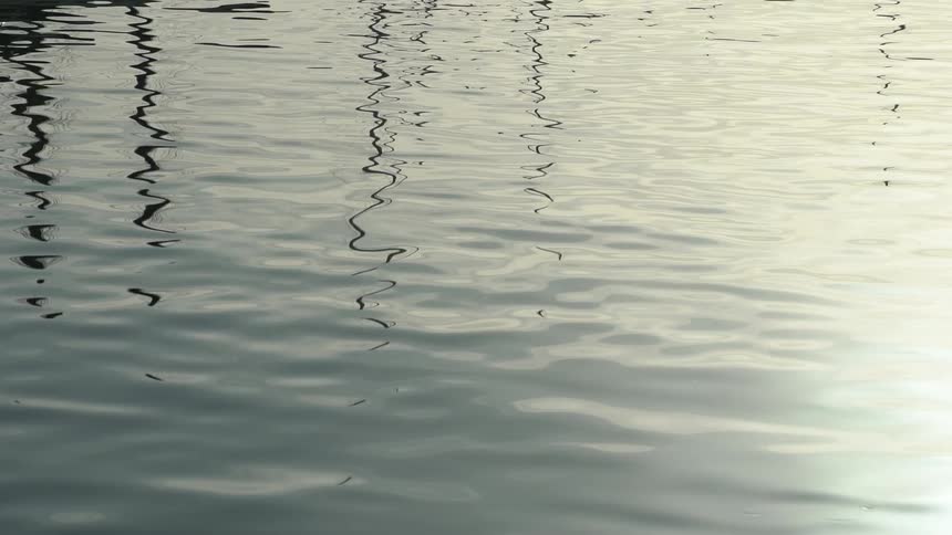 Closeup view of calm water with gentle ripples reflecting grey tones of an overcast sky