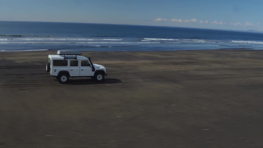 Suv rolling along a beach on a fairly clear day