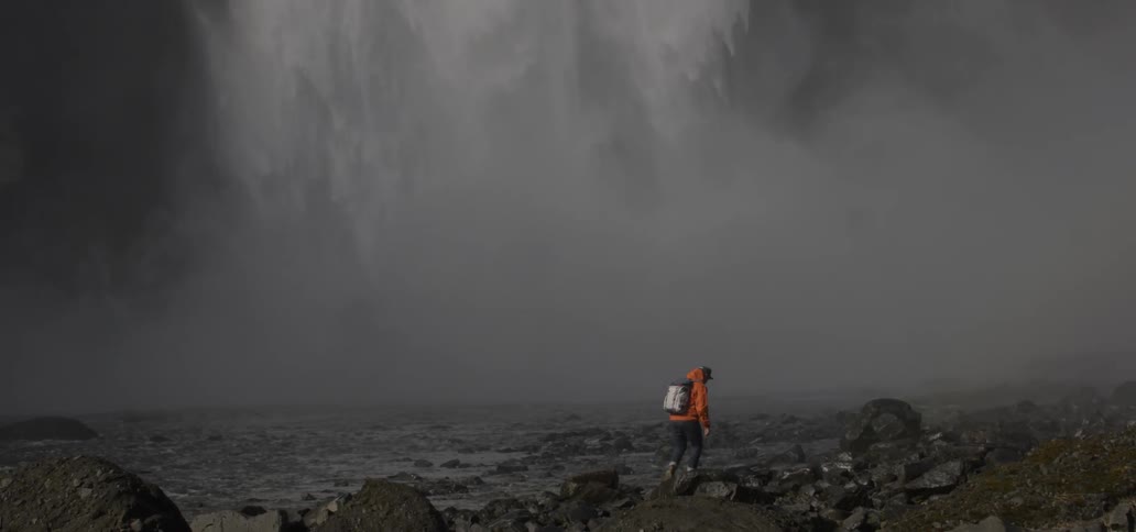 A man walks towards a waterfall