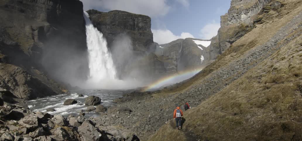 Two people hike to a waterfall