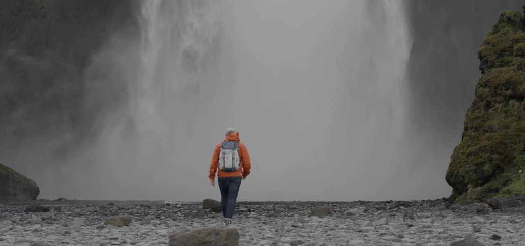 A person walks towards a waterfall