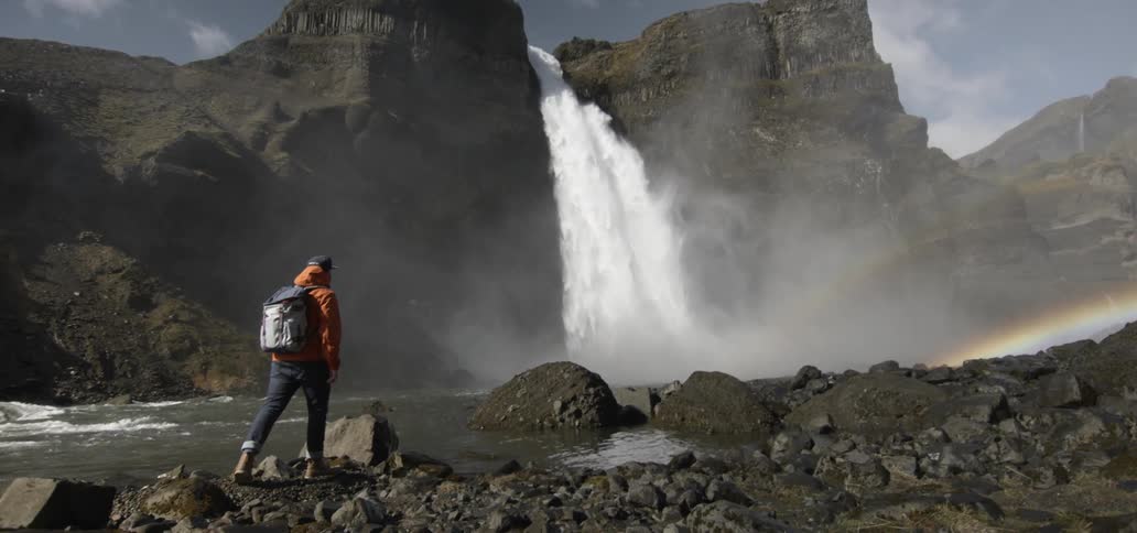 A backpacker walks towards a waterfall