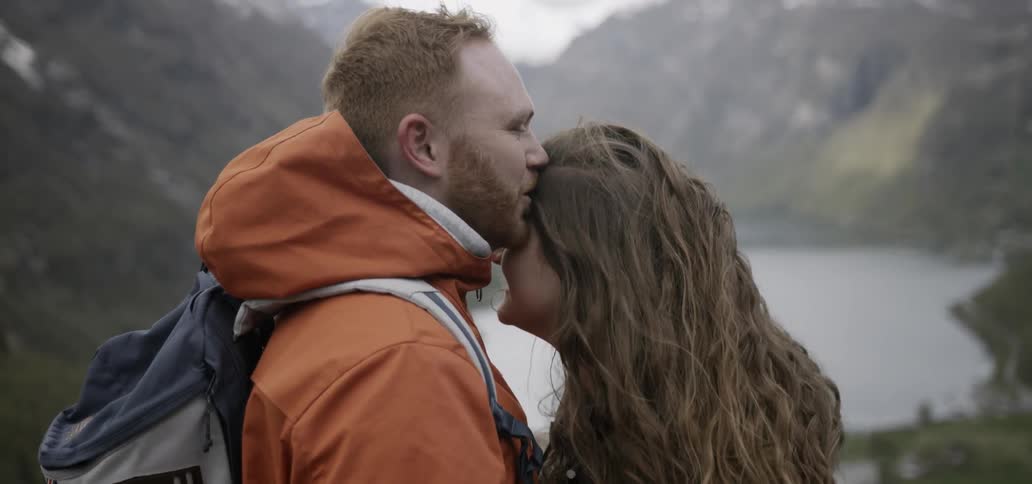 Couple standing closely and lovingly high above a river in the wilderness