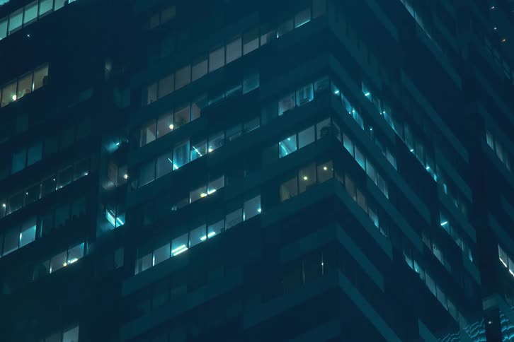 The lights of the apartments in a large condominium building that are blinking