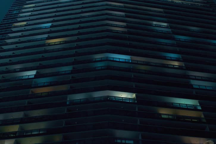 Time lapse of a building in the city at night with lights in the windows flickering quickly