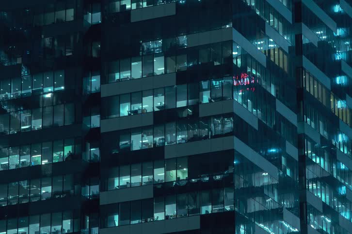 A time lapse of a high rise office building in a city at night with lights in different levels turning on and off