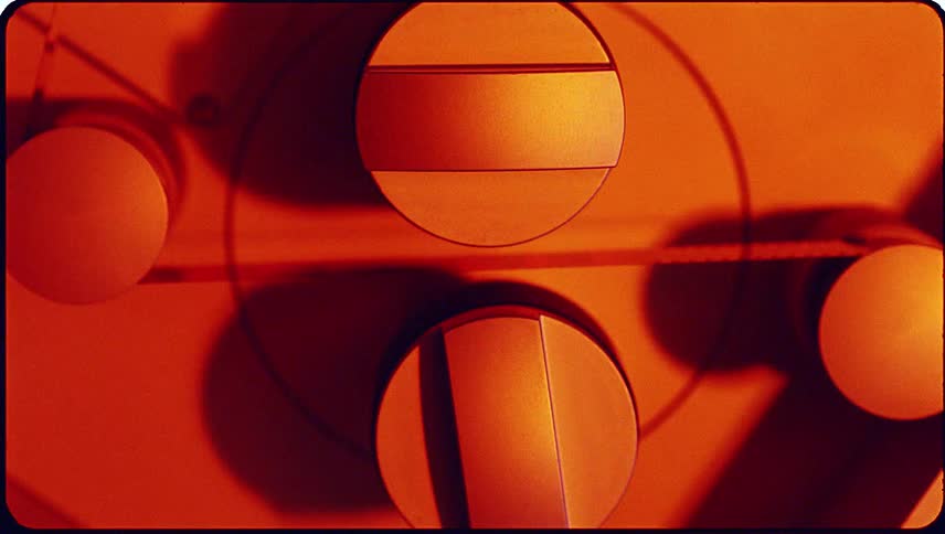 Film running through a machine as red and blue lights flash on the machine