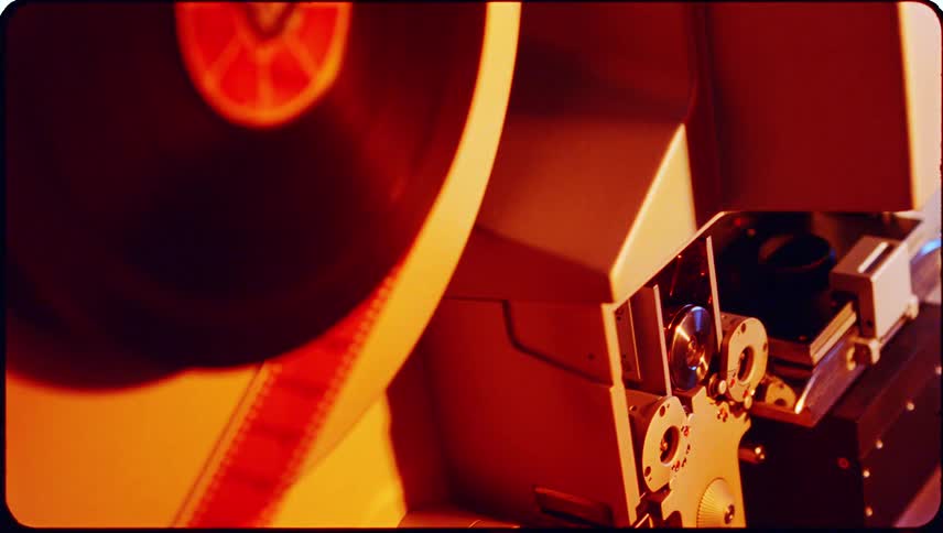 A closeup view of a machine revealing a strip of negative film unwinding from a roll