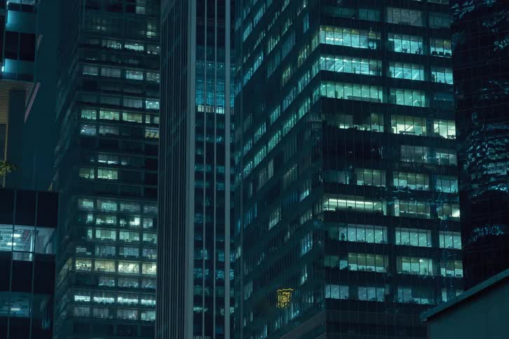 The exterior of modern high rise buildings at night with illuminated windows