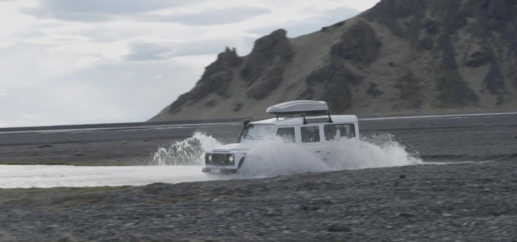 An suv plows through water on a beach