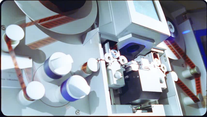 A large machine scanning and rotating film through an area with flashing lights