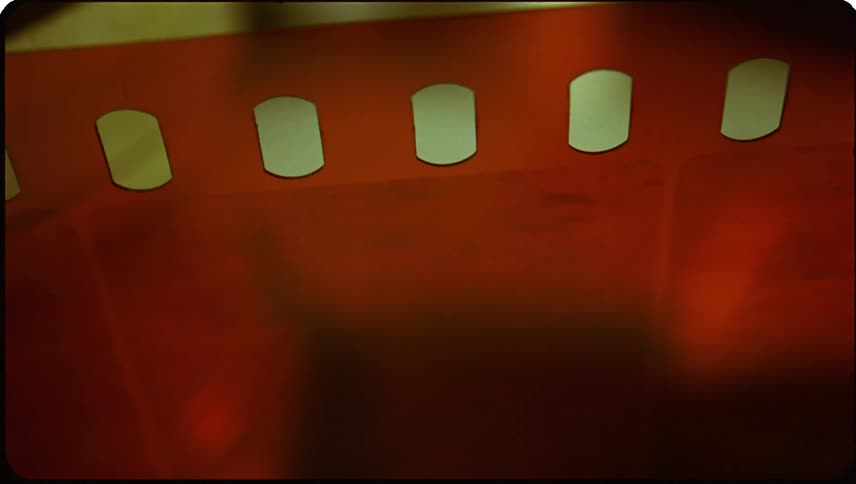 A closeup of a strip of reddish brown film negative with transparent frames