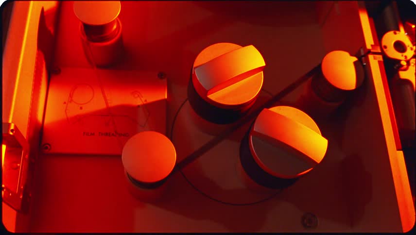 Film rotating through a machine with red lights flashing around it