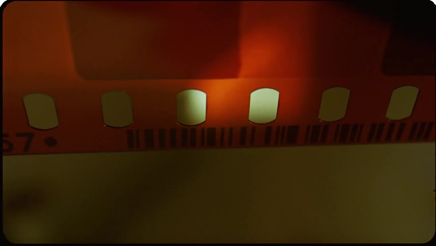 Closeup view of a section of a reddish brown film strip with transparent frames