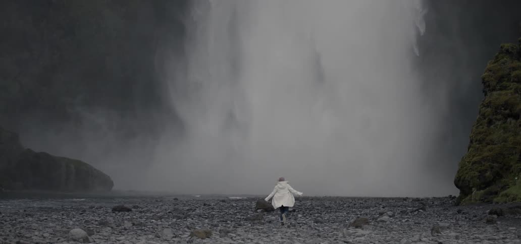 A person runs towards a waterfall