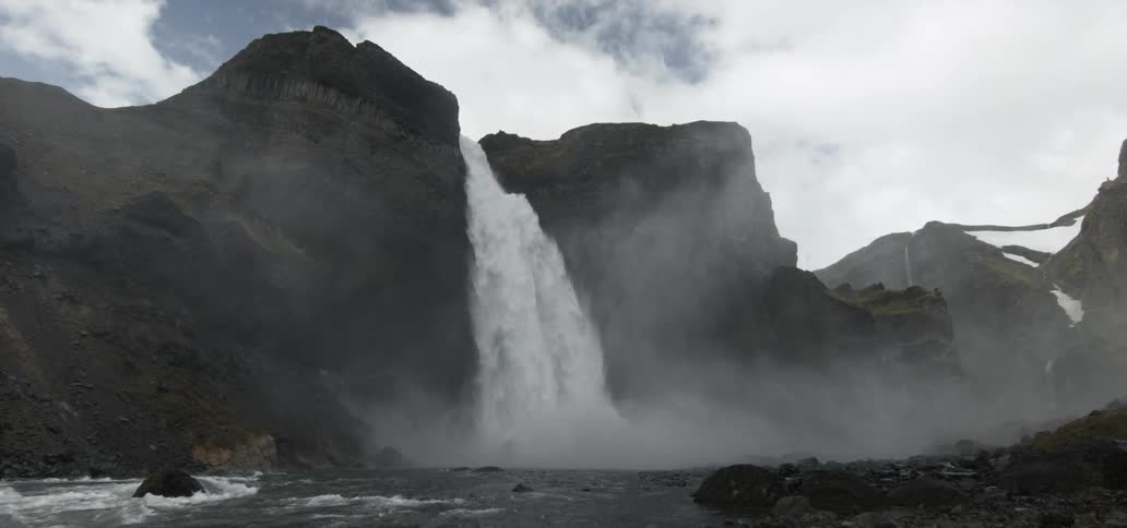 A waterfall gushes over a cliff into the river below