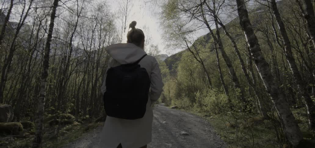 A woman walks down a forest path