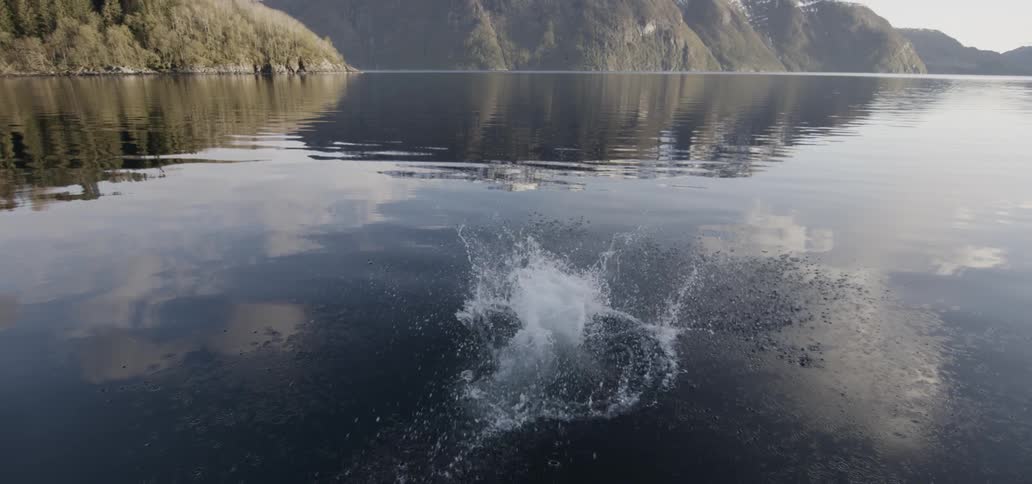 A man cannonballs into a mountain lake