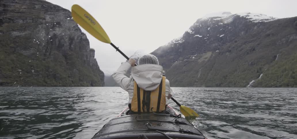 Kayaker paddling through calm waters towards some mountains
