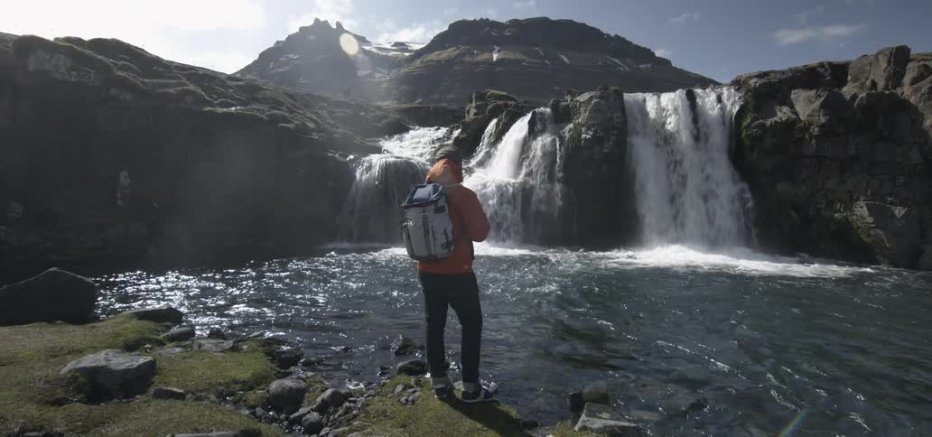 A man standing by a small waterfall