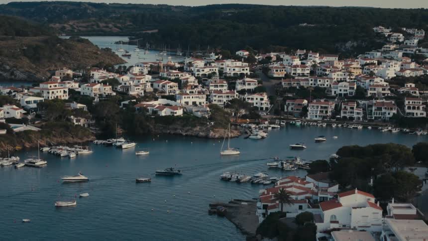 Boats float in the harbor bordering a coastal town