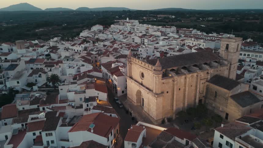 An aerial view of a quaint town cityscape with whitewashed buildings and a prominent church