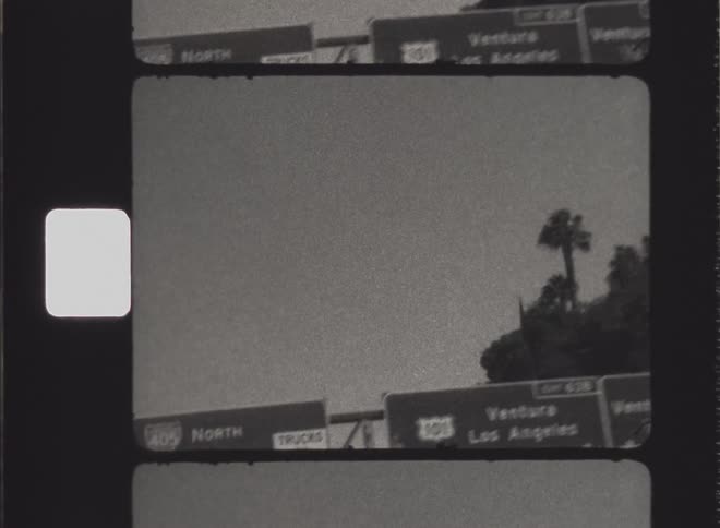 An old image of a movement passing by a traffic sign and everything is black and white