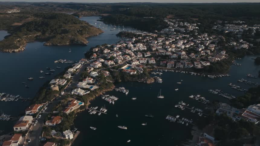 An aerial view of a town of many houses on a hill in the middle of two water channels with many boats on the surface