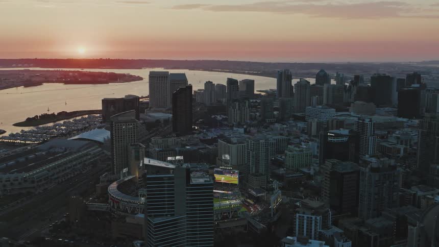 An aerial view of a city skyline with a baseball stadium in the foreground