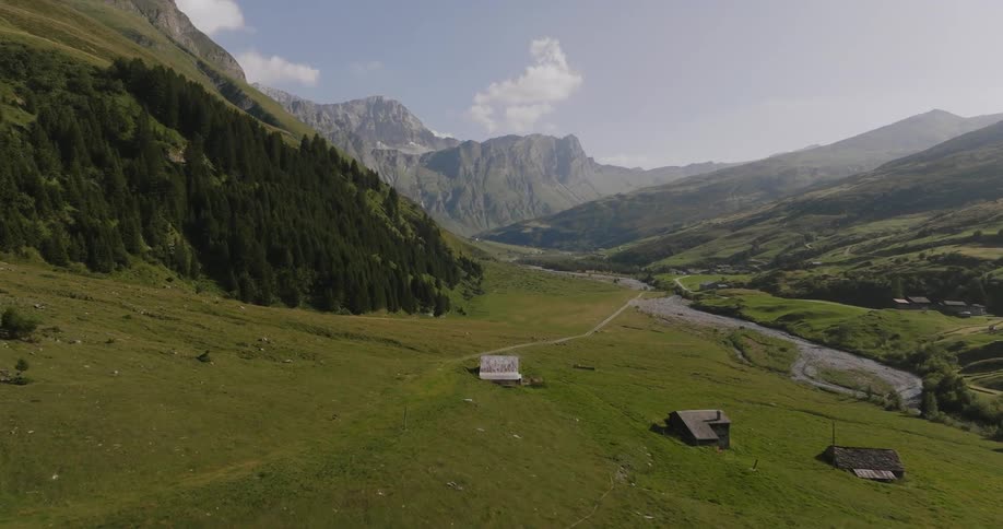 Aerial of farm houses in a river valley surrounded by mountains