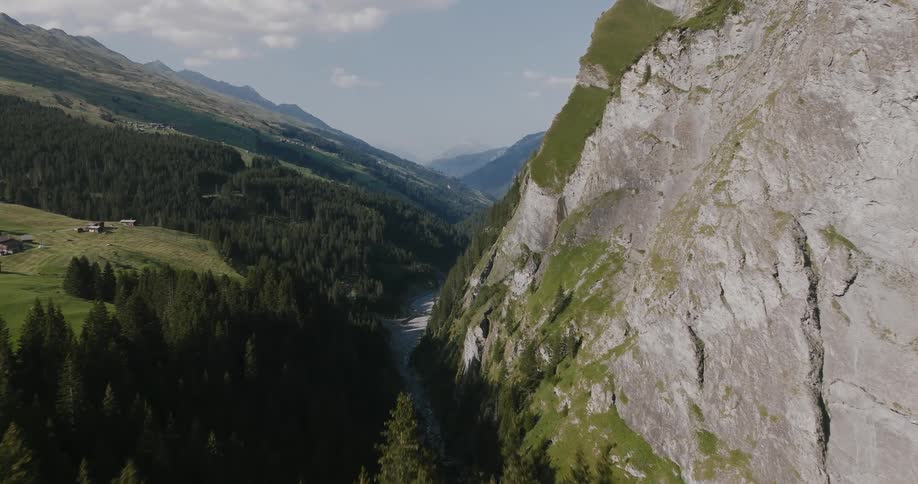 An aerial view of a valley where there is a mountain of rocks and on the other side there is a pine forest