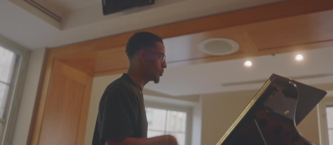 Man standing near a piano in a building in downtown gestures while talking
