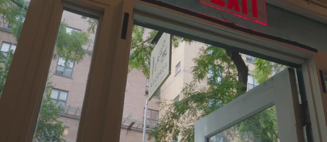A sign hangs over an open door to a building in a city