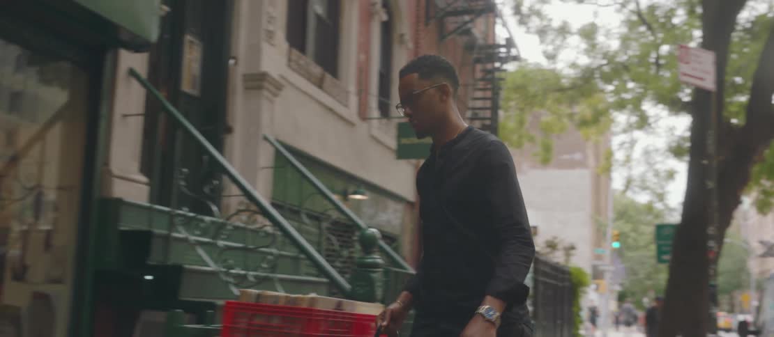 A young man walking on the sidewalk entering a record store in the city